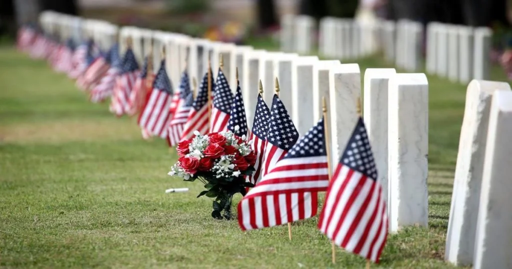 Flags placed at headstones in a cemetery on Memorial Day, symbolizing honor and remembrance.